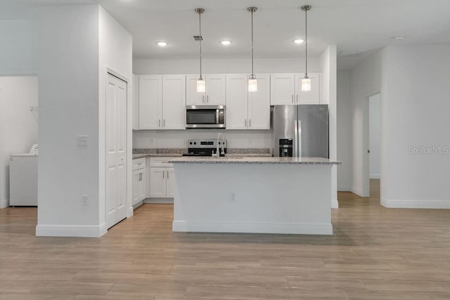 kitchen with washer / clothes dryer, an island with sink, hanging light fixtures, stainless steel appliances, and white cabinets