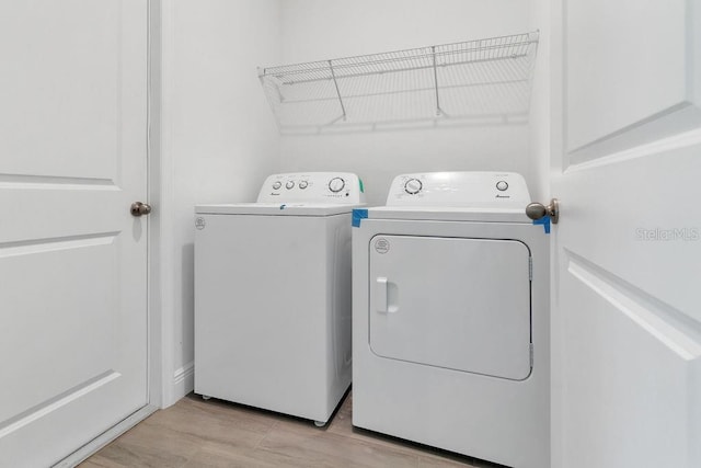 laundry room with light hardwood / wood-style flooring and washing machine and clothes dryer