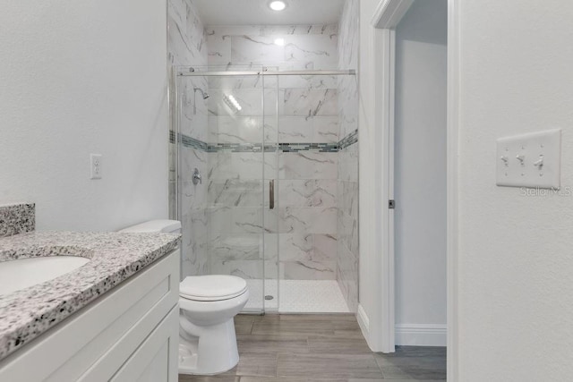 bathroom featuring toilet, a shower with shower door, hardwood / wood-style floors, and vanity