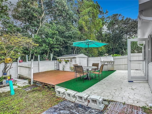 view of patio with a shed, area for grilling, and a wooden deck