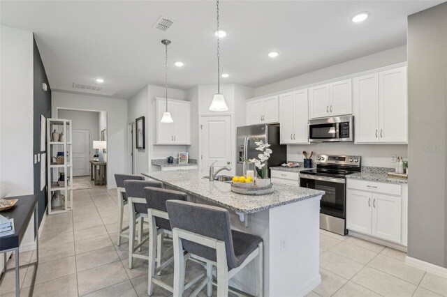 kitchen featuring appliances with stainless steel finishes, white cabinetry, and an island with sink