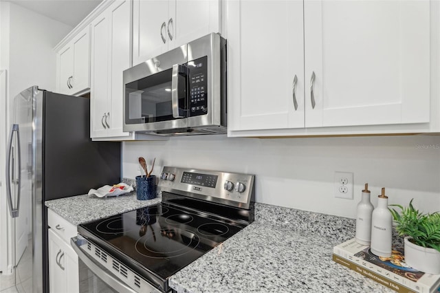 kitchen with stainless steel appliances, light stone counters, and white cabinetry