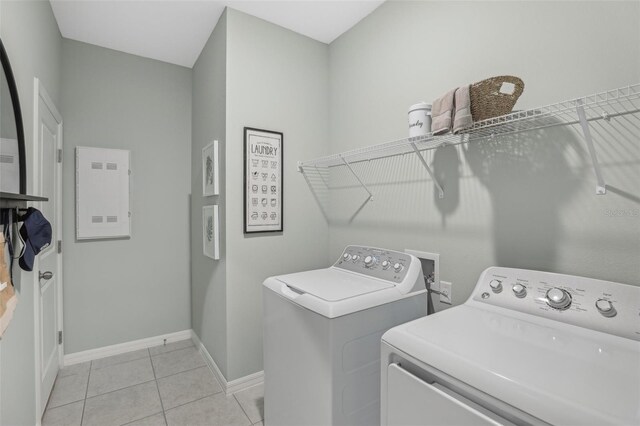 clothes washing area featuring light tile patterned flooring, electric panel, and separate washer and dryer