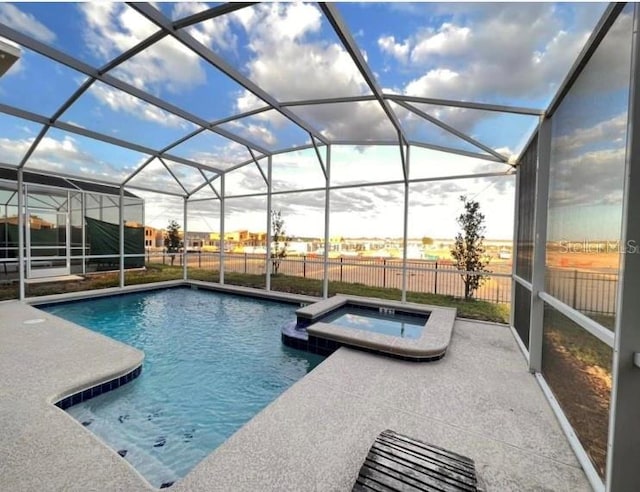 pool at dusk with an in ground hot tub, glass enclosure, and a patio area