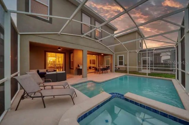 pool at dusk with an outdoor hangout area, a patio, an in ground hot tub, and a lanai