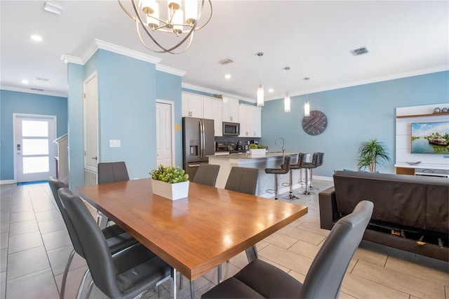 dining room featuring a notable chandelier, light tile patterned flooring, sink, and ornamental molding