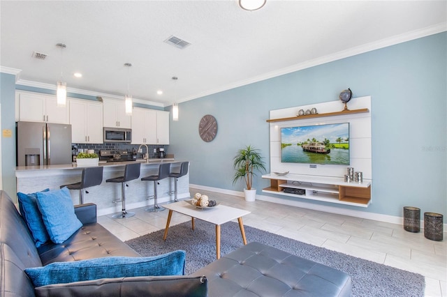 living room with ornamental molding, sink, and light tile patterned floors