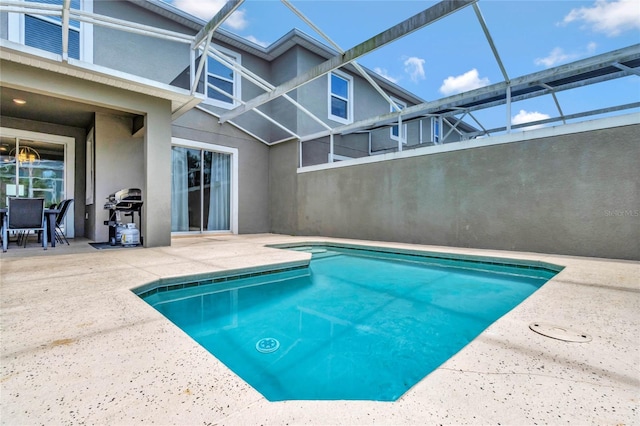 view of pool with grilling area, a patio area, and a lanai