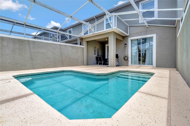 view of swimming pool with glass enclosure and a patio