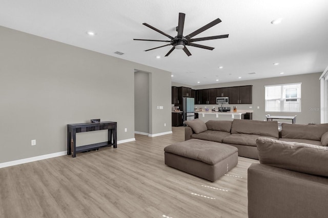 living room featuring light wood-type flooring and ceiling fan