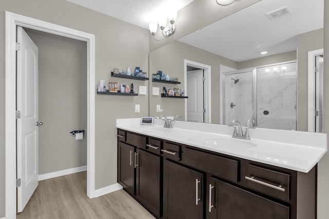 bathroom with a shower with door, vanity, hardwood / wood-style floors, and a textured ceiling