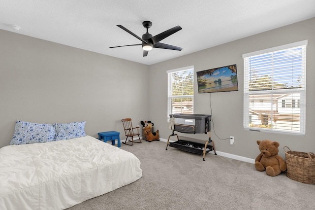 carpeted bedroom with ceiling fan, a wood stove, and multiple windows