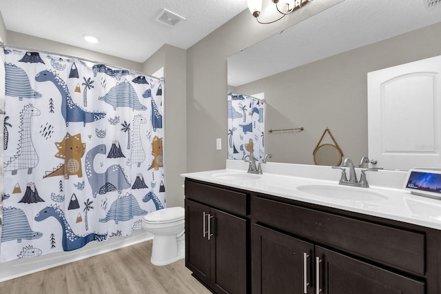 full bathroom with hardwood / wood-style flooring, toilet, shower / tub combo with curtain, vanity, and a textured ceiling