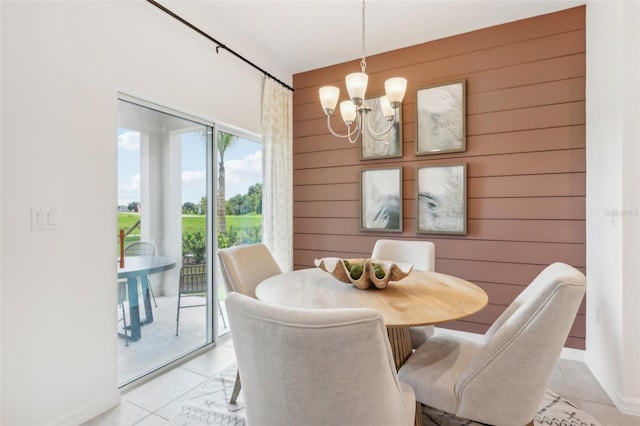 tiled dining room featuring wood walls and an inviting chandelier