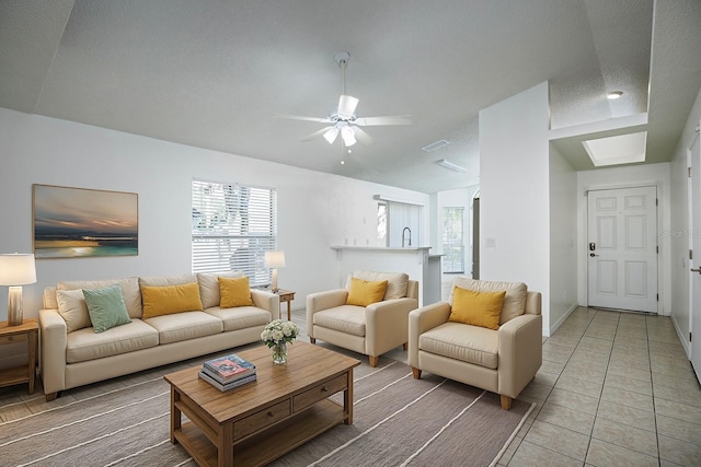 living room featuring ceiling fan, a textured ceiling, and tile patterned floors