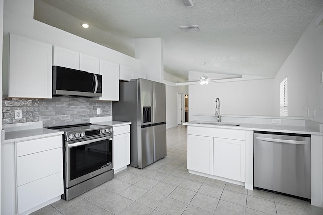 kitchen featuring lofted ceiling, stainless steel appliances, white cabinets, sink, and a textured ceiling