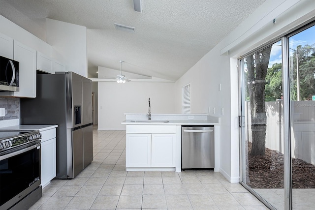 kitchen with lofted ceiling, light tile patterned floors, sink, white cabinetry, and stainless steel appliances