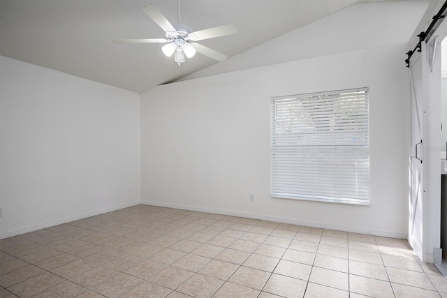 empty room featuring ceiling fan, a barn door, vaulted ceiling, and light tile patterned floors