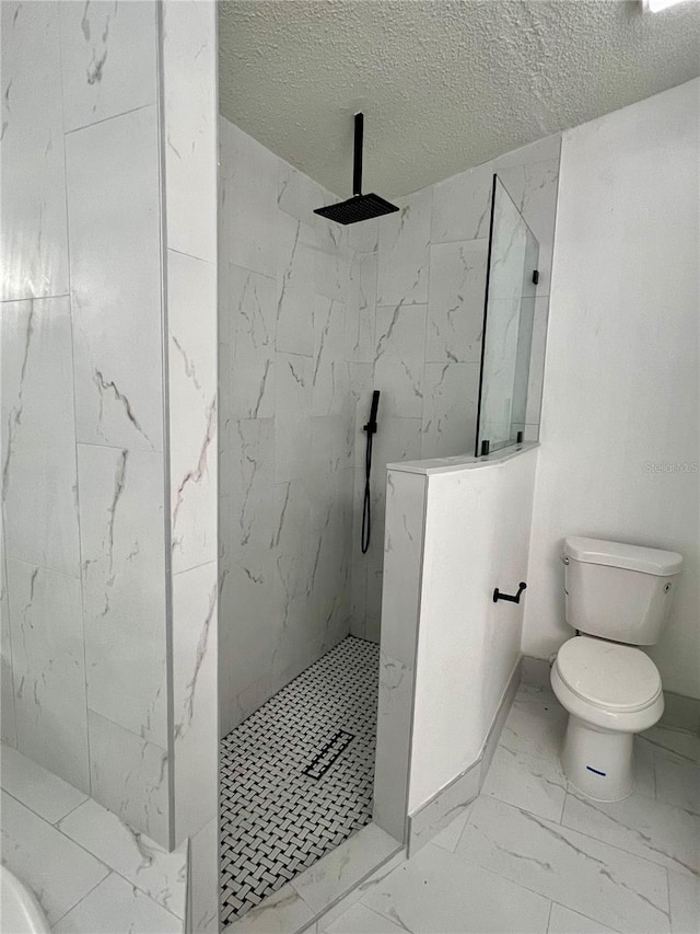 bathroom with tiled shower, toilet, and a textured ceiling