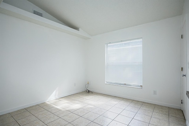 tiled spare room featuring vaulted ceiling and a textured ceiling