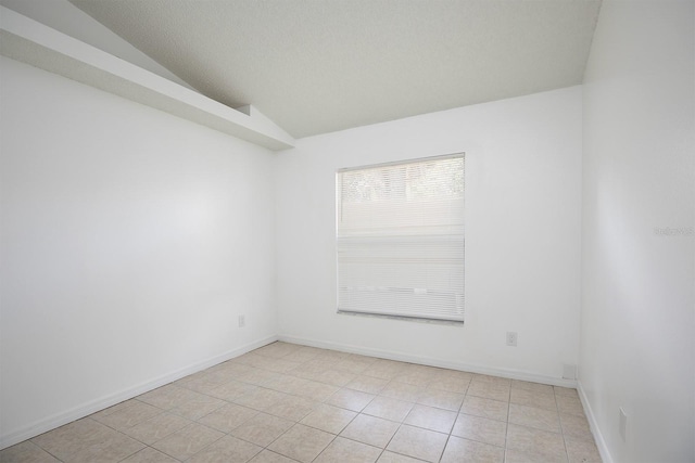 tiled empty room with lofted ceiling and a textured ceiling