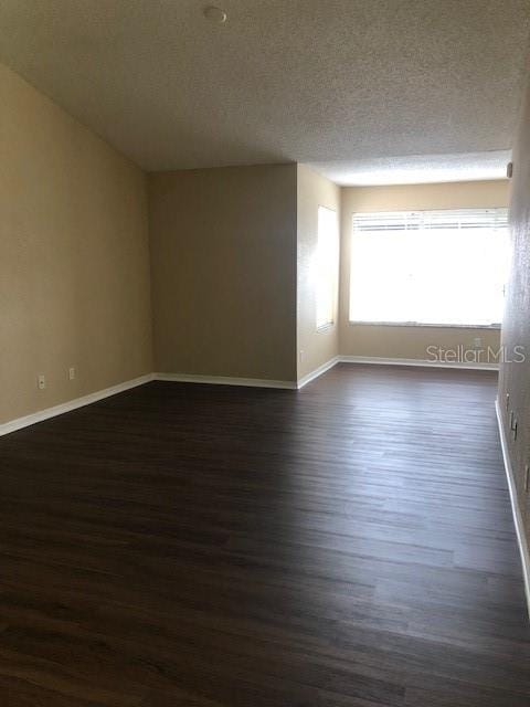 empty room featuring dark hardwood / wood-style floors and a textured ceiling