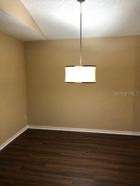 unfurnished room featuring a textured ceiling and dark hardwood / wood-style flooring