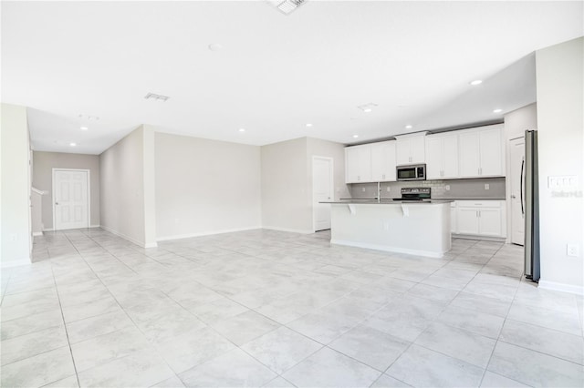 kitchen with white cabinets, sink, appliances with stainless steel finishes, a center island with sink, and light tile patterned floors