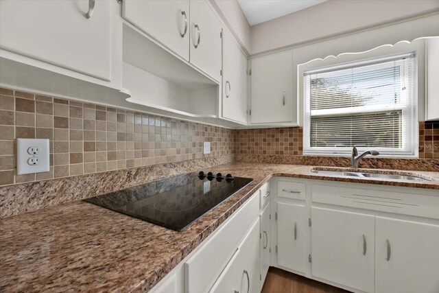 kitchen featuring black electric stovetop, decorative backsplash, white cabinets, and sink