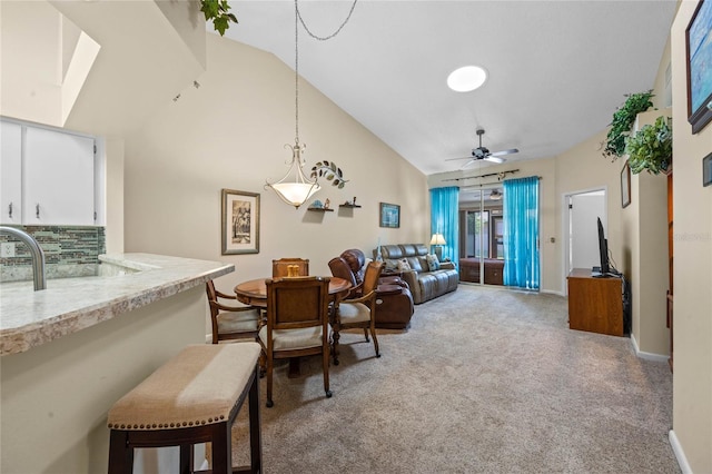 carpeted dining area featuring ceiling fan and vaulted ceiling