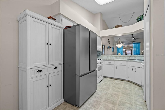 kitchen featuring ceiling fan, stainless steel fridge, sink, white cabinetry, and white stove