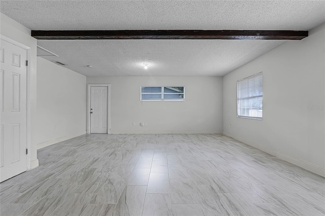 spare room featuring beamed ceiling and a textured ceiling