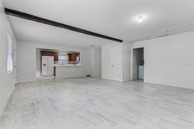 unfurnished living room with beamed ceiling, sink, and a textured ceiling