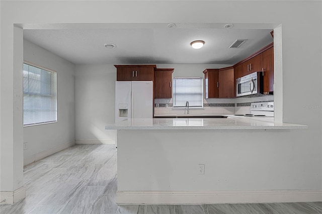 kitchen featuring light stone counters, tasteful backsplash, white appliances, kitchen peninsula, and a textured ceiling