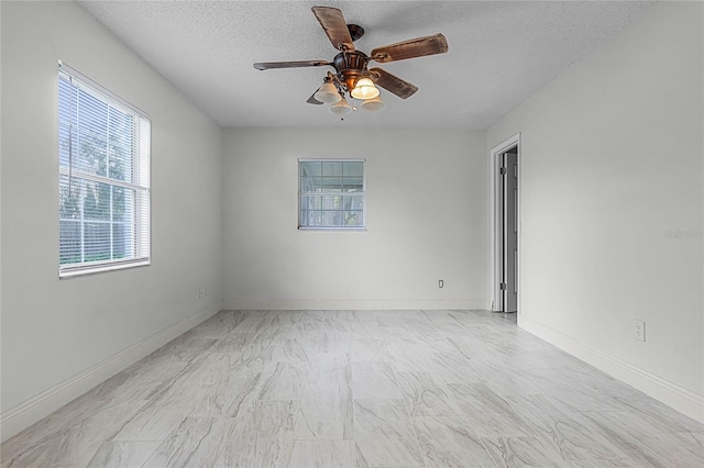 empty room with ceiling fan, a textured ceiling, and a healthy amount of sunlight