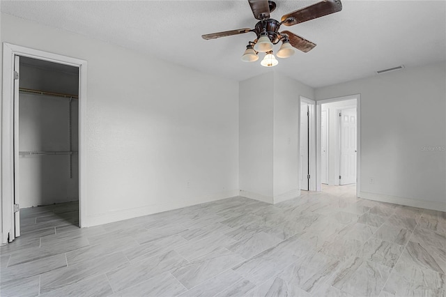 unfurnished bedroom featuring ceiling fan, a textured ceiling, a closet, and a spacious closet