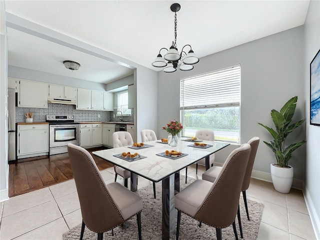 dining space with sink, light hardwood / wood-style flooring, a chandelier, and a wealth of natural light