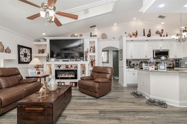 living room featuring hardwood / wood-style flooring, ceiling fan with notable chandelier, lofted ceiling, and ornamental molding