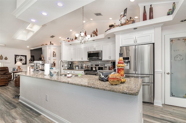 kitchen with white cabinets, appliances with stainless steel finishes, vaulted ceiling, and a large island