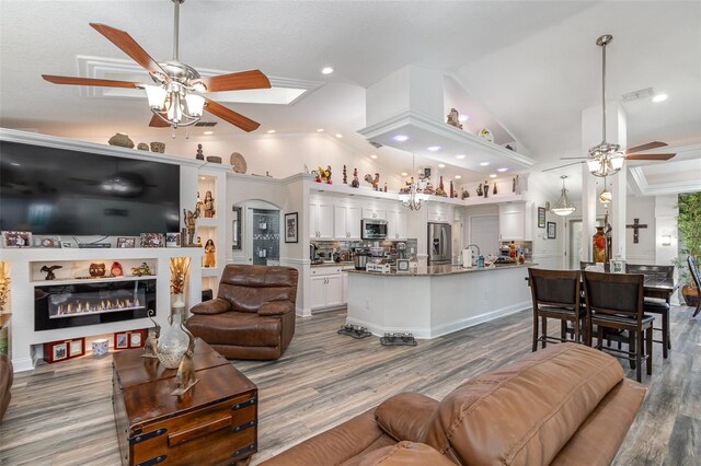 living room featuring ceiling fan, wood-type flooring, sink, and vaulted ceiling