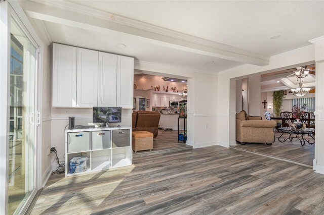 kitchen with ornamental molding, beam ceiling, an inviting chandelier, white cabinets, and hardwood / wood-style floors