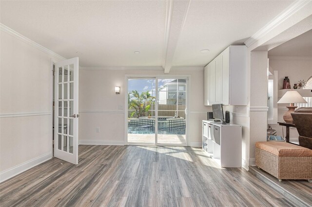 interior space featuring beamed ceiling, ornamental molding, a textured ceiling, and hardwood / wood-style flooring