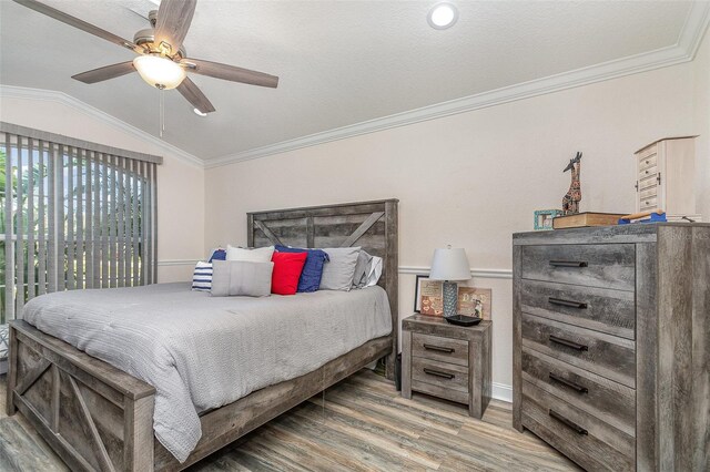 bedroom with a textured ceiling, vaulted ceiling, ceiling fan, crown molding, and hardwood / wood-style floors