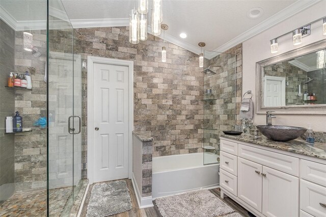 bathroom featuring hardwood / wood-style floors, vanity, bath / shower combo with glass door, crown molding, and vaulted ceiling