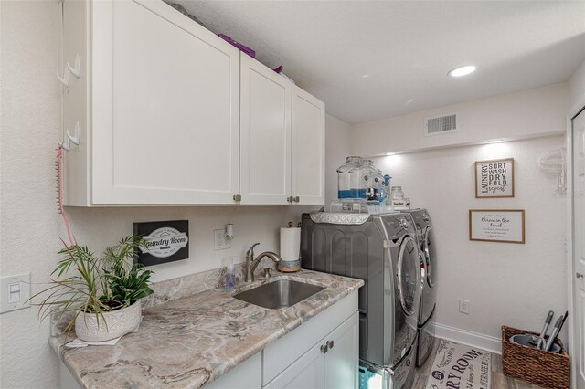 laundry room featuring washer and clothes dryer, cabinets, and sink