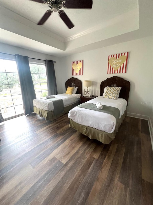 bedroom with access to outside, dark hardwood / wood-style floors, a raised ceiling, and ceiling fan