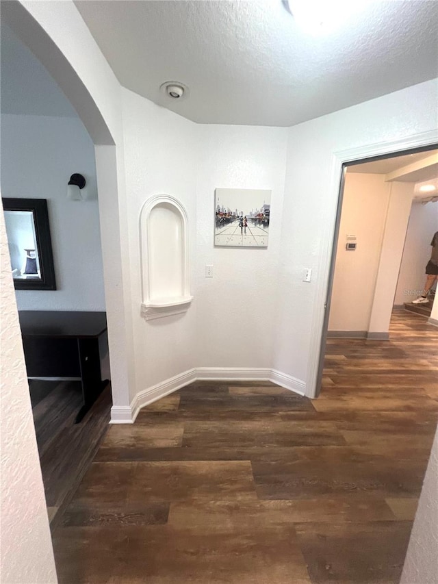 hall featuring dark wood-type flooring and a textured ceiling