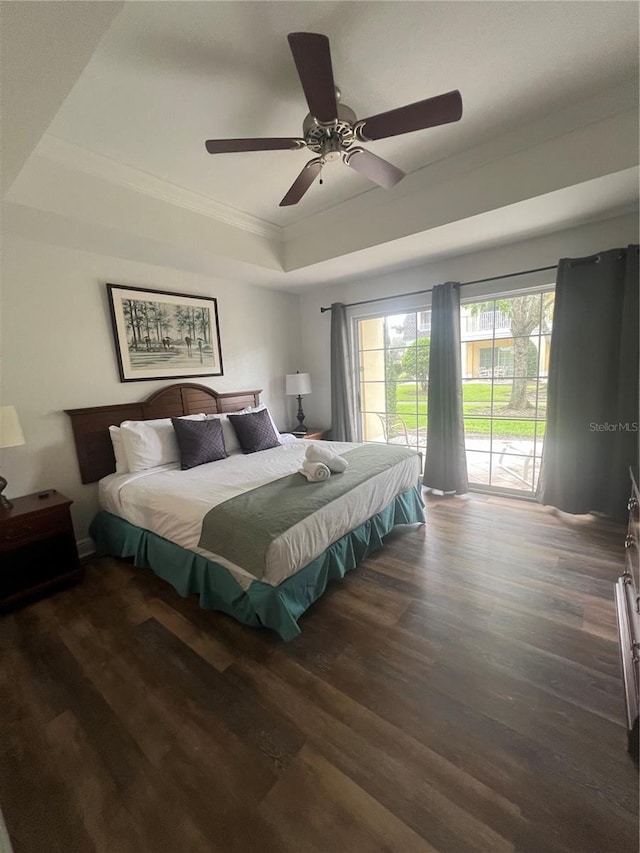 bedroom with access to outside, dark hardwood / wood-style floors, a tray ceiling, and ceiling fan