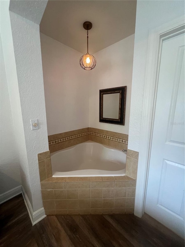 bathroom with wood-type flooring and a relaxing tiled tub