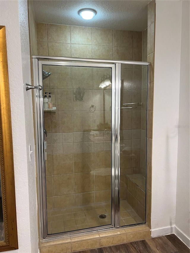 bathroom with hardwood / wood-style flooring, a textured ceiling, and an enclosed shower